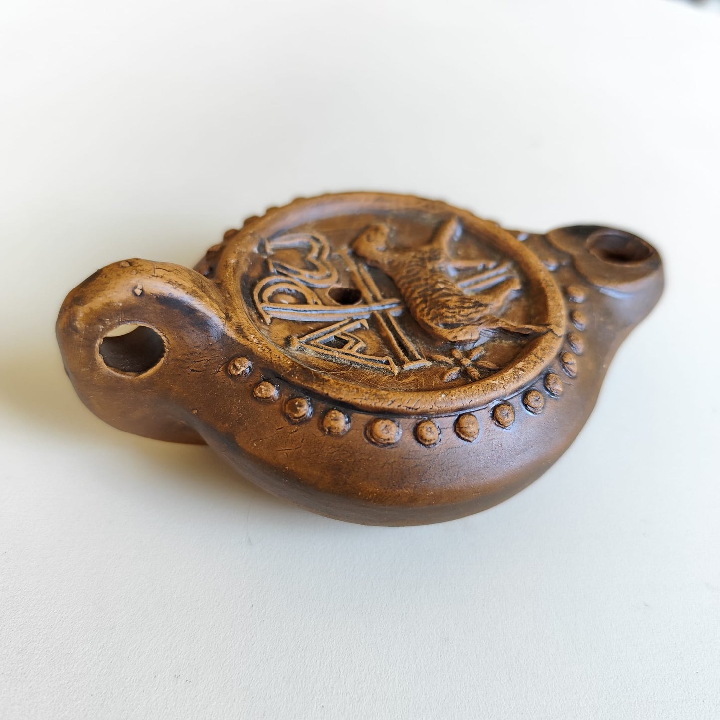 Detalle lateral y del asa de la lucerna paleocristiana con chi-ro y cordero