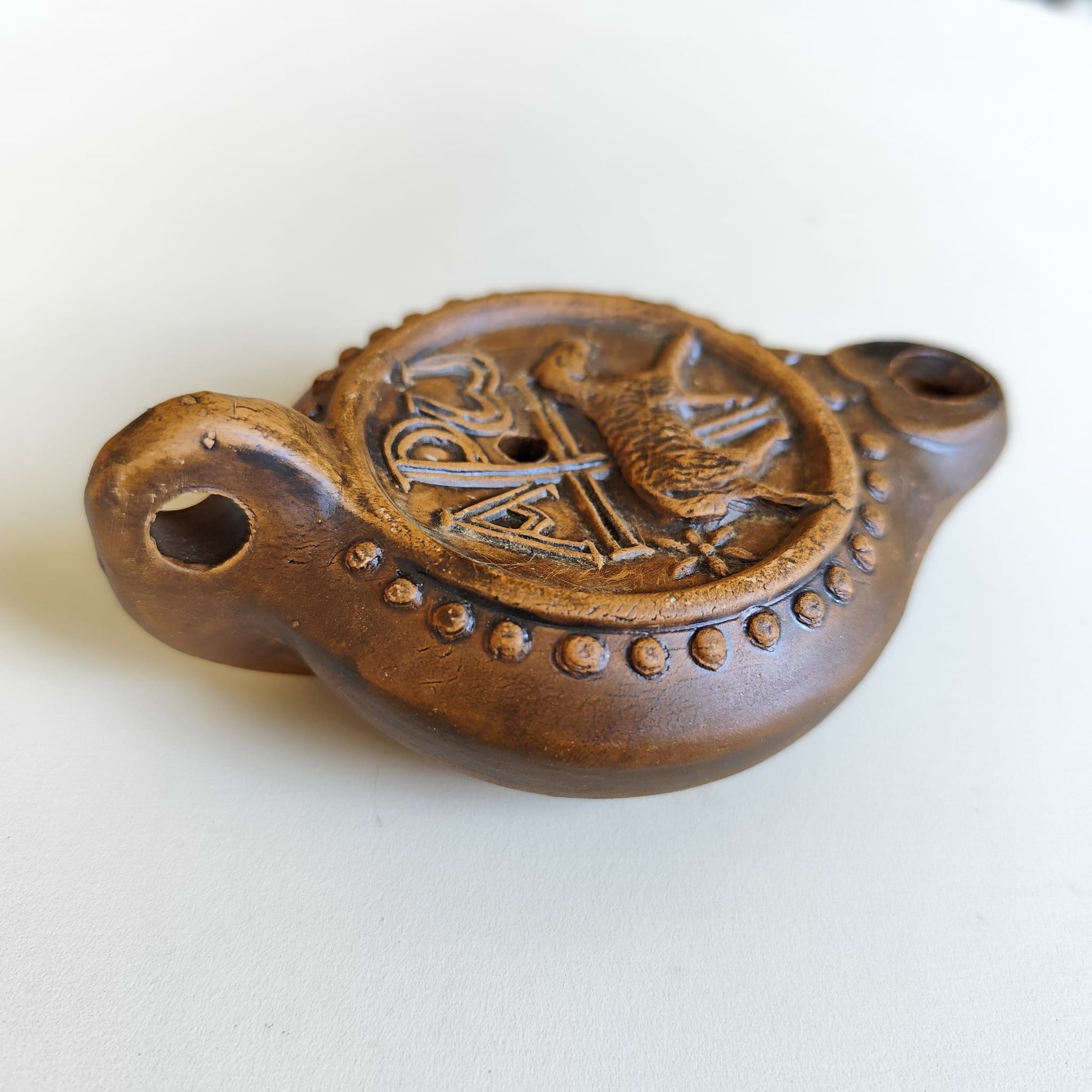 Detalle lateral y del asa de la lucerna paleocristiana con chi-ro y cordero