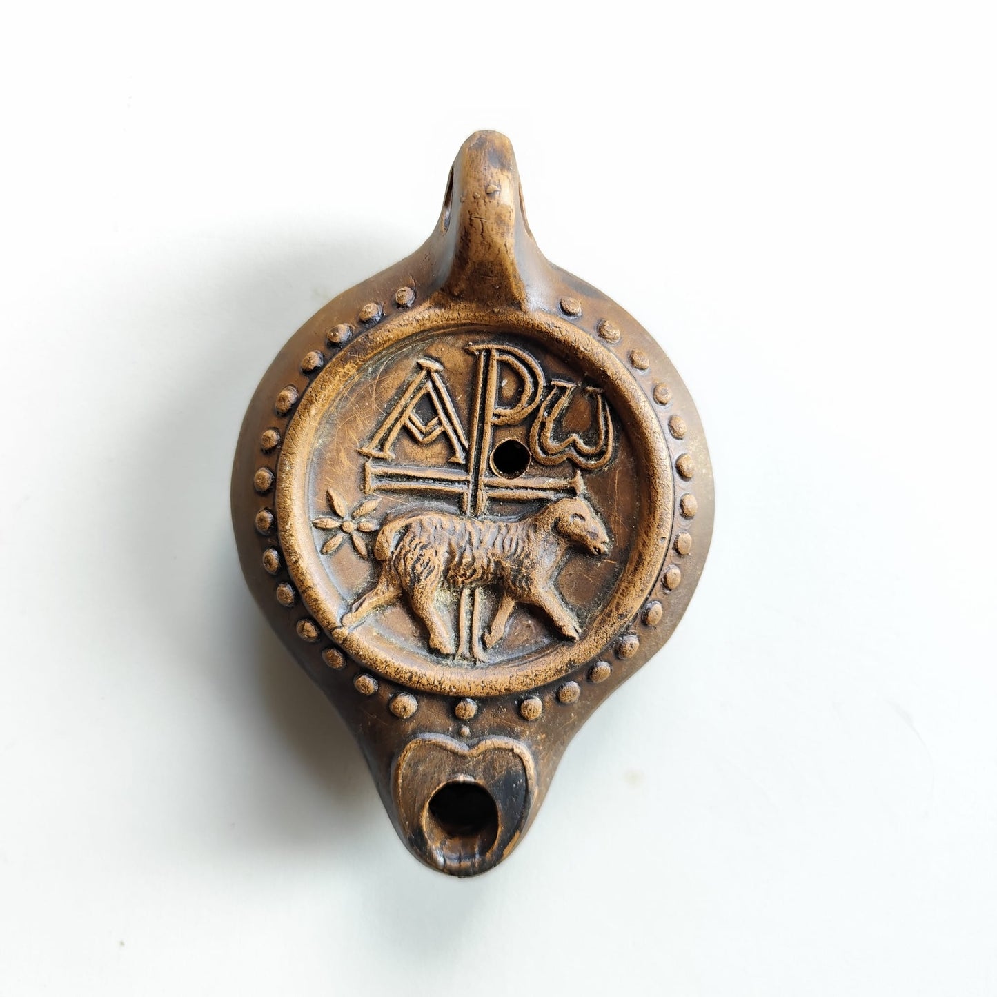 Detalle frontal de lucerna paleocristiana. Chi-ro y cordero. 